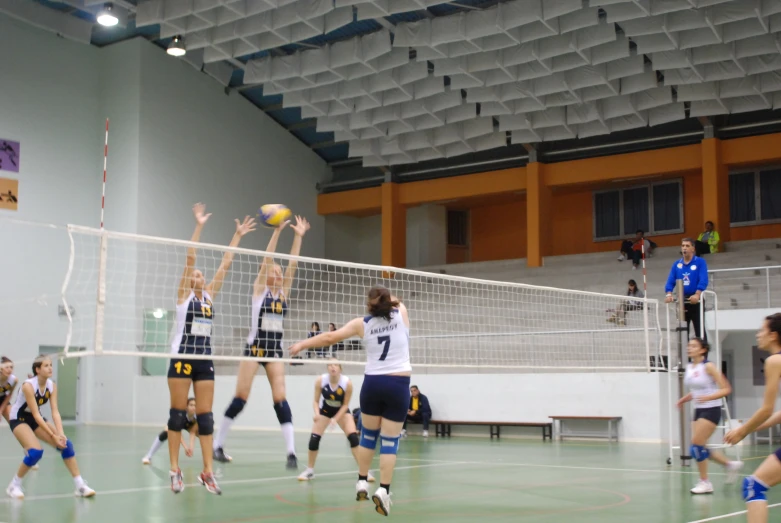 volleyball players reaching up to hit the ball