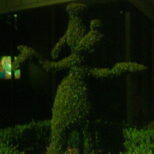 a fake grass tree that is outside in the dark