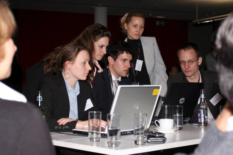 a group of people looking at an open laptop