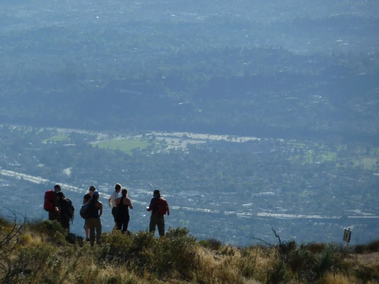 three people hiking up a hill toward the city