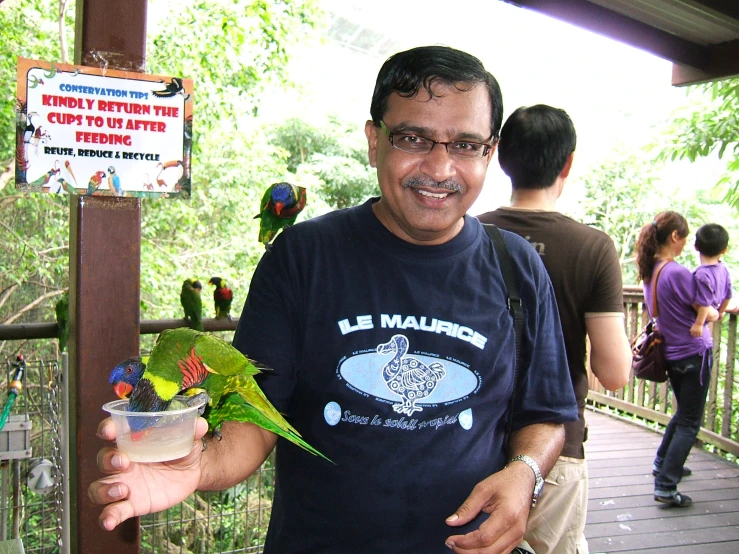 a man smiles as he holds a drink with a parrot on it