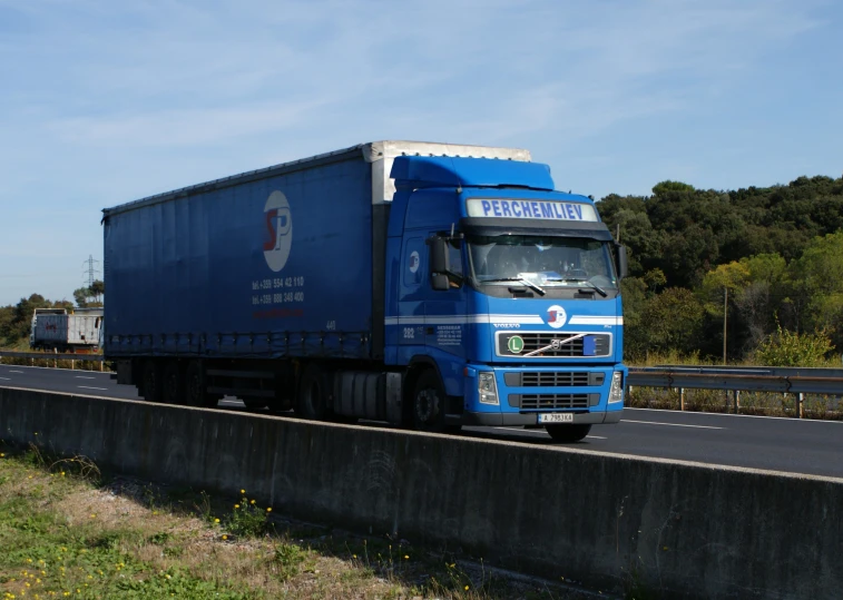 a blue truck on road next to wall