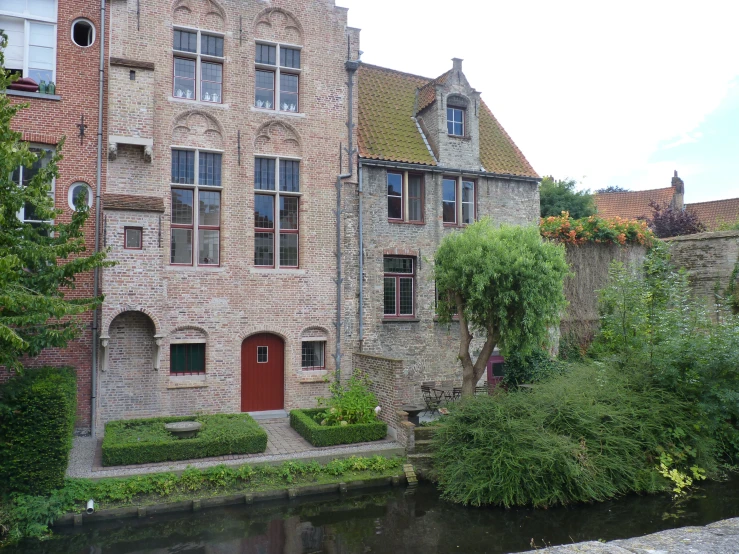 a brick house with a red door next to some trees