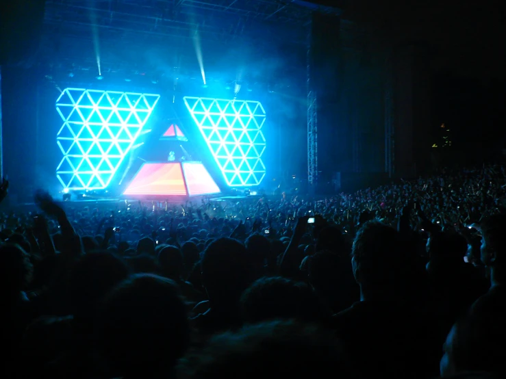 the crowd in front of the stage are watching someone perform on a large screen