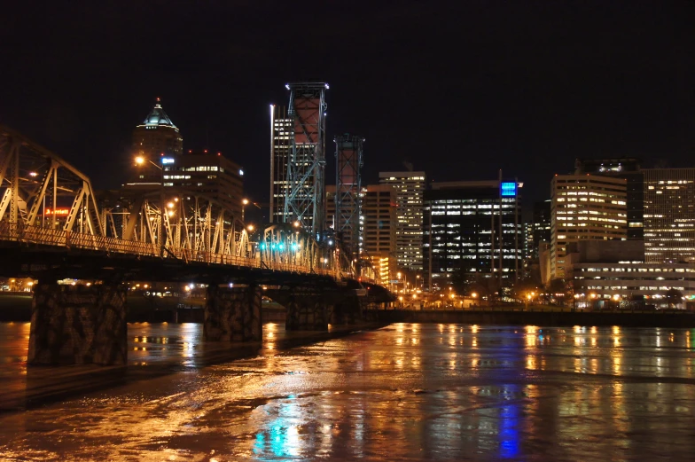 a night view of the city skyline with buildings over water