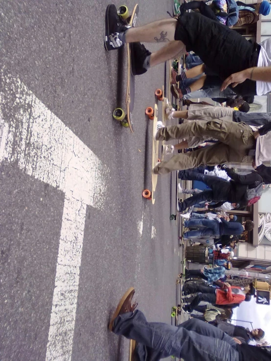 people standing on the side of a road while one is skateboarding