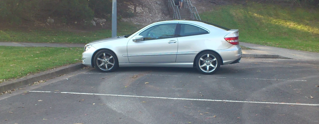 silver car parked in a parking lot next to grass