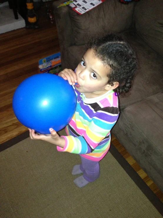 a little girl that is playing with a blue balloon