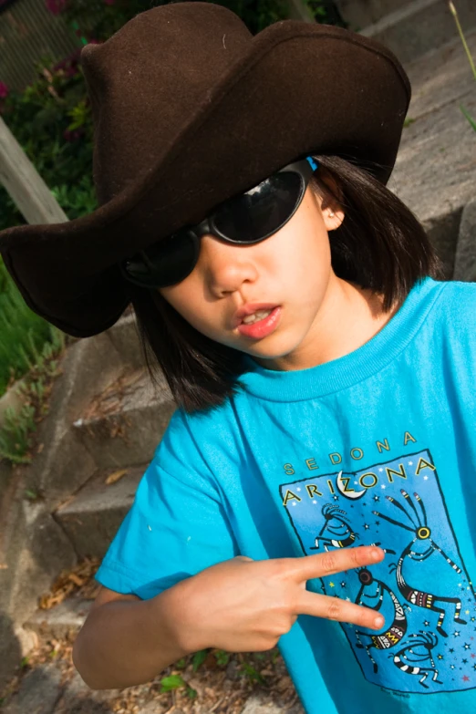 the girl wearing a hat and sunglasses is pointing her finger