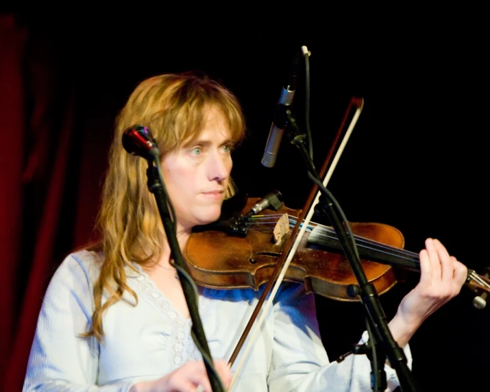 a woman holding a violin and performing at a concert