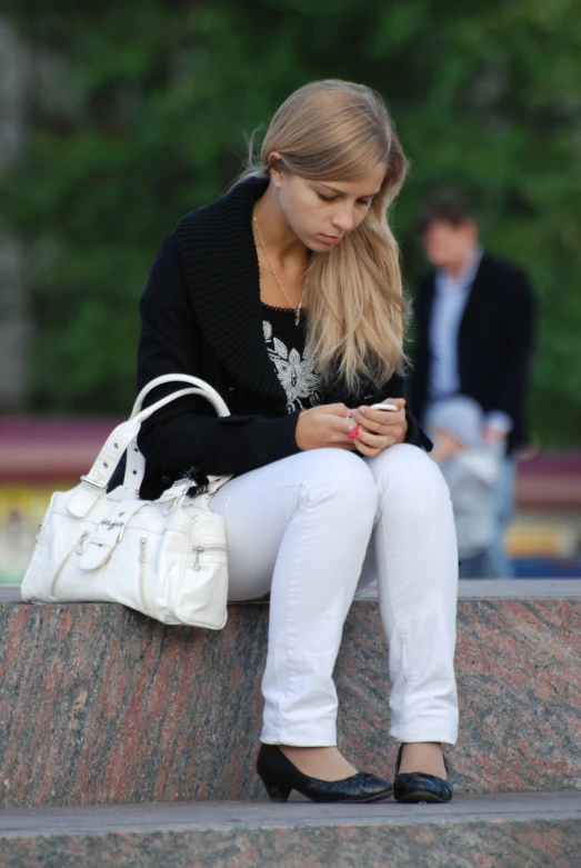 a woman with her handbag sitting on a wall