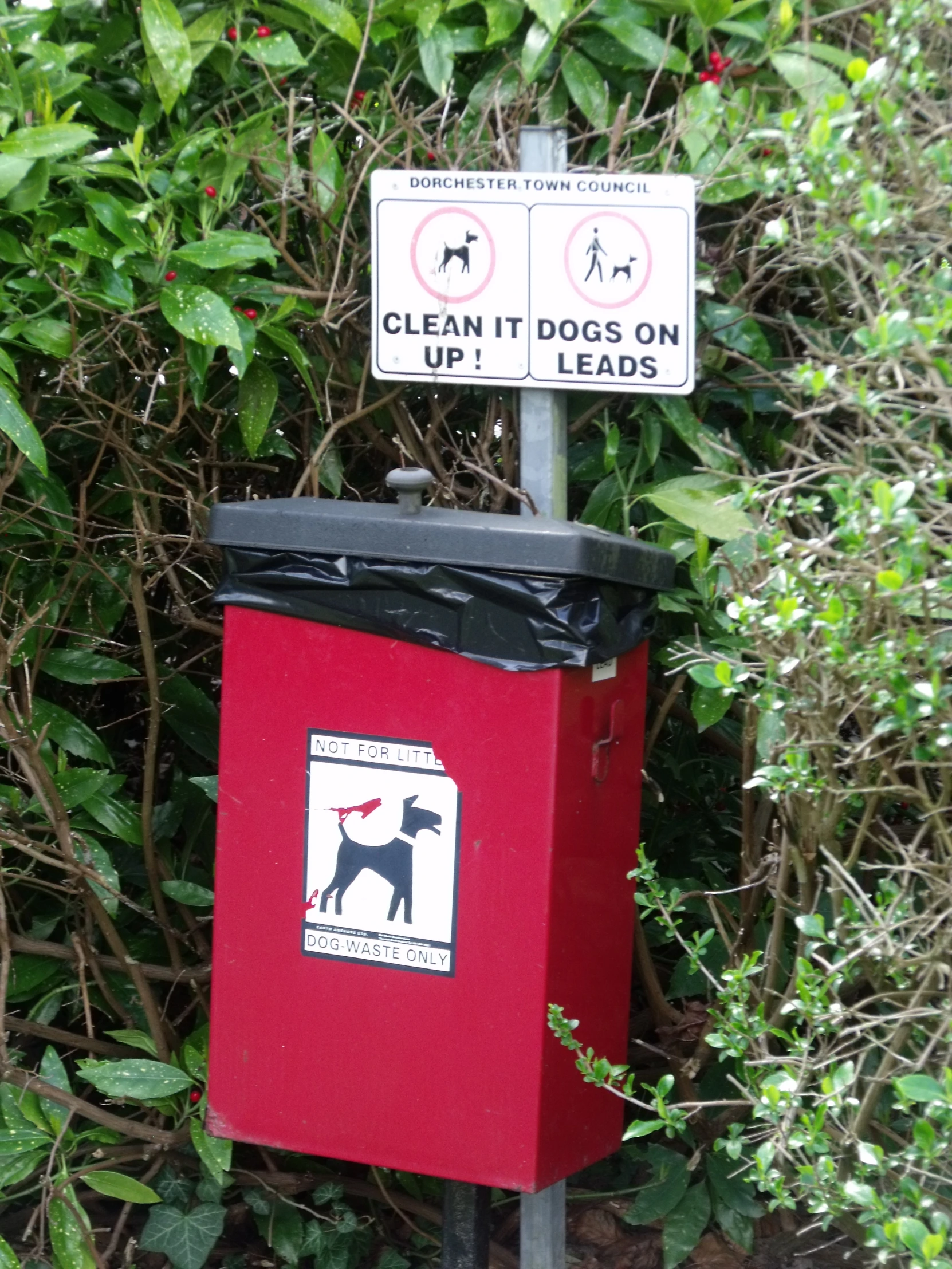 a garbage can sitting next to a red bin with a sign stating it is clean