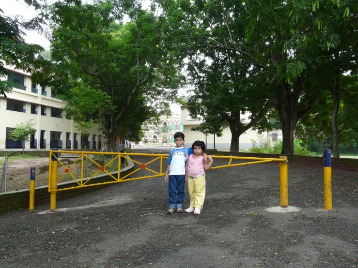 two children posing on the road between some trees