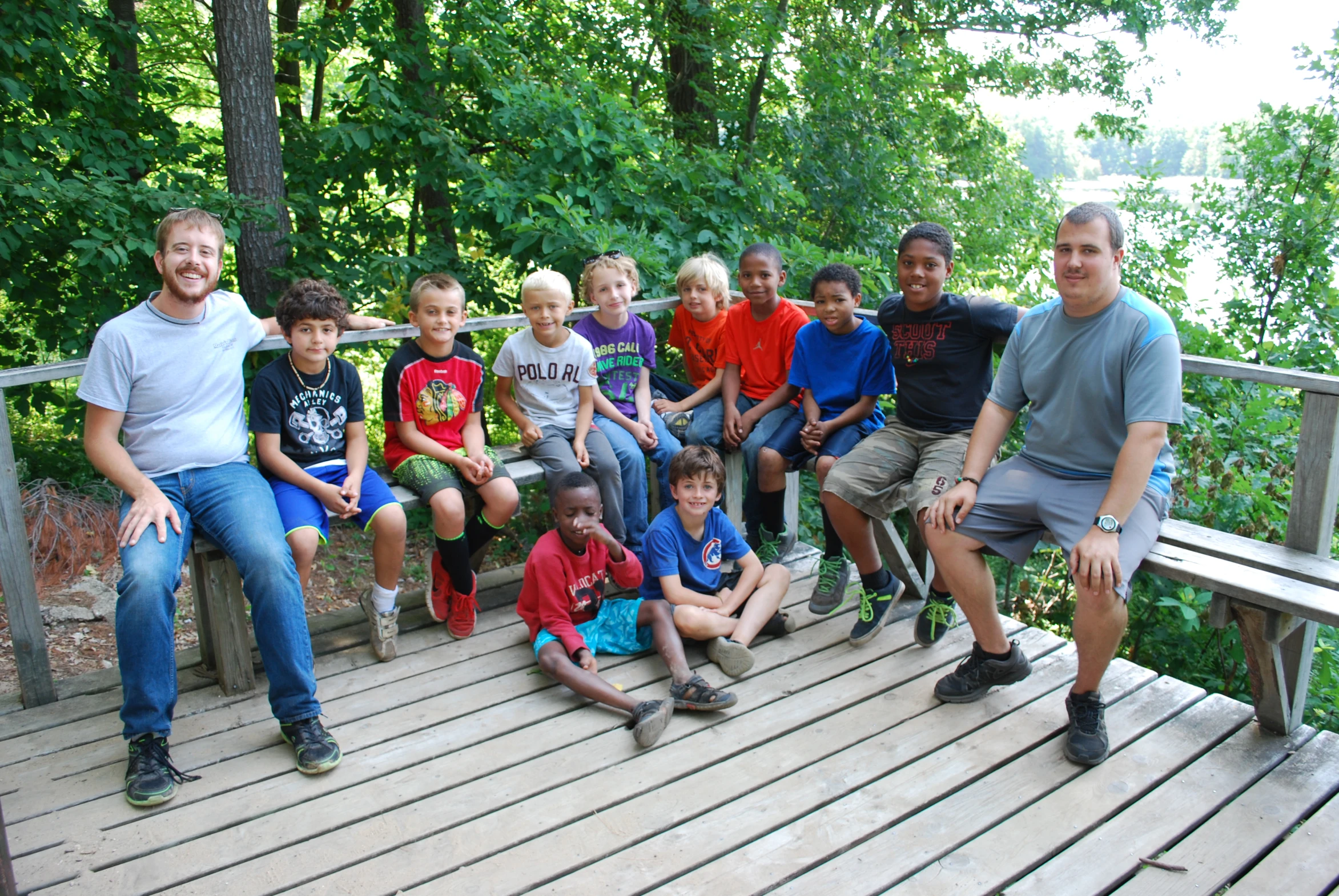 a group of people pose on a deck near a lake