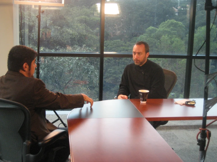 two men sitting at a table talking