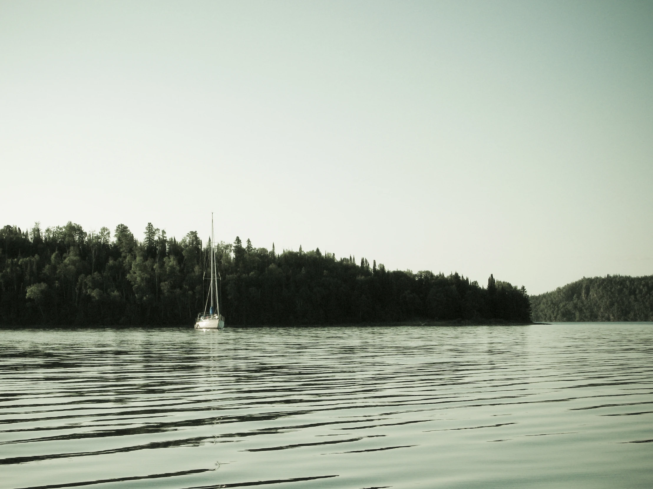 sailboat on a lake near a large island with trees