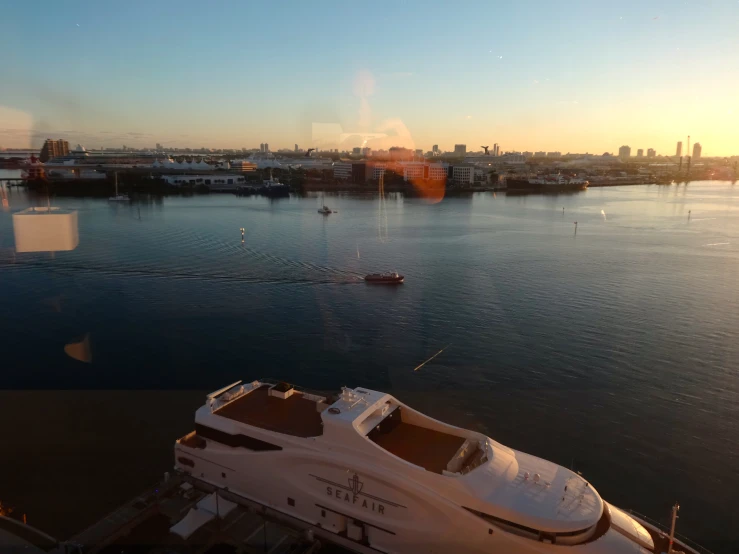 a white yacht is in the water by a big city