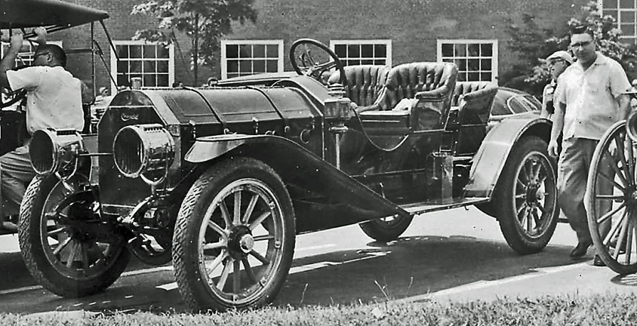 a man stands with an old fashioned car