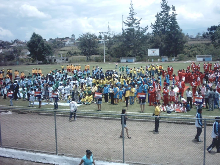 a large group of people in uniforms are standing near a chain link fence