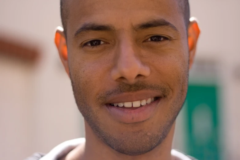 a man with an orange shirt smiles at the camera