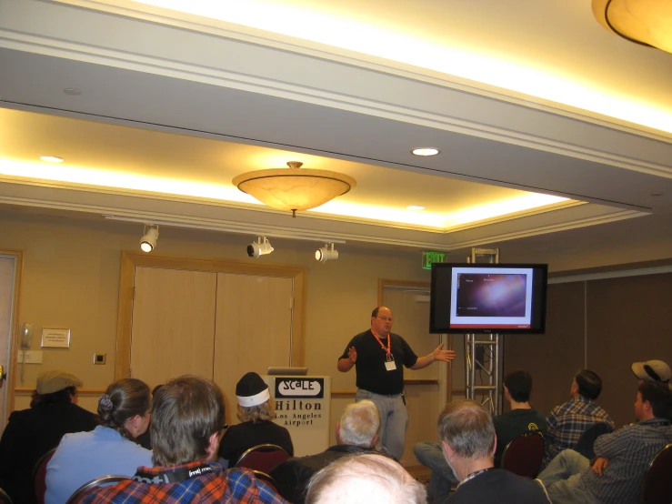 there is a man standing in front of a crowd in a room