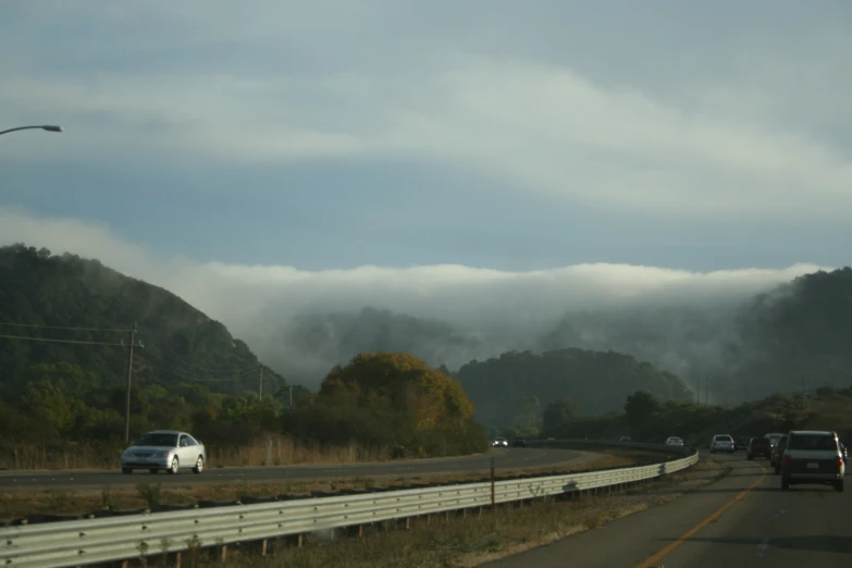 some cars drive on a highway that is winding