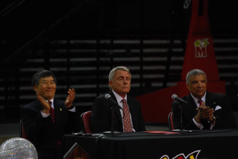 the men in suits are clapping at a podium