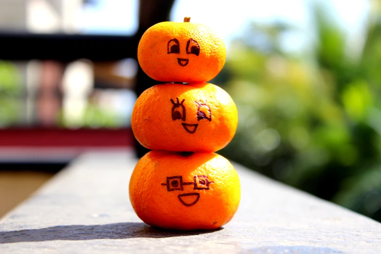 a group of three oranges that have drawn faces on them