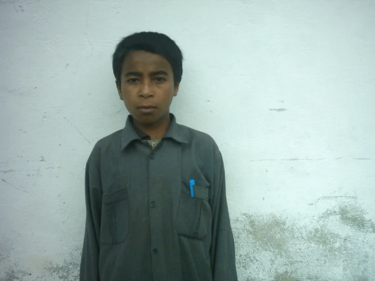 a boy in front of a wall with a tooth brush in his pocket