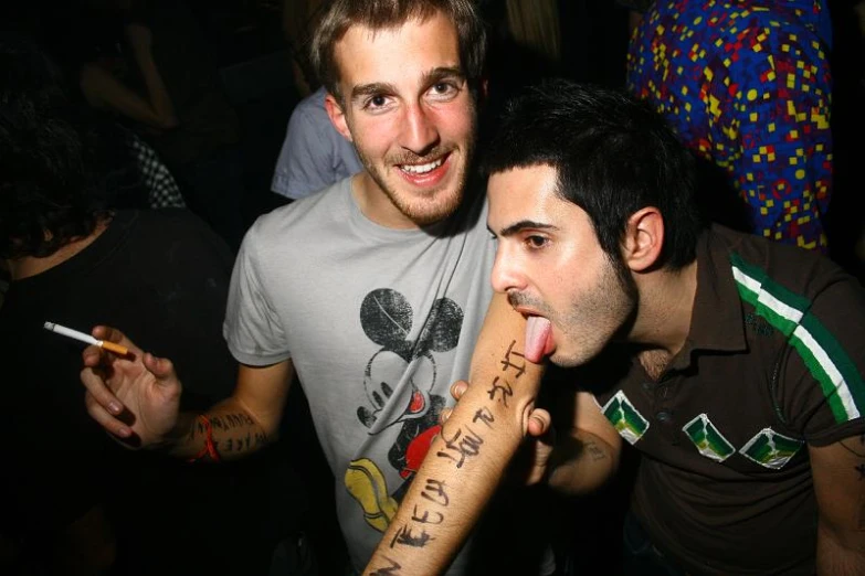 the young man with a tattoo on his arm is licking the cigarette