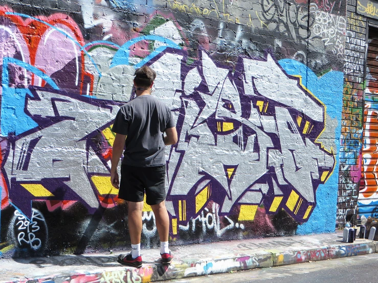 the man stands in front of the wall covered with graffiti