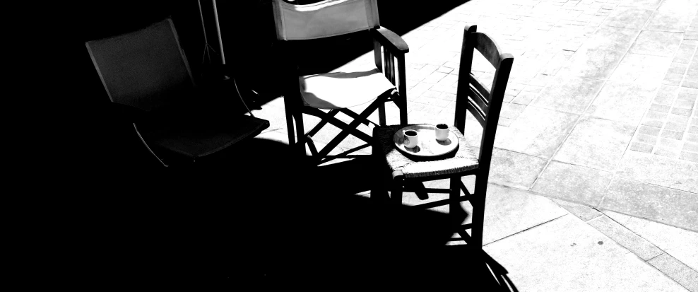 a cat sitting on top of a wooden chair next to a table