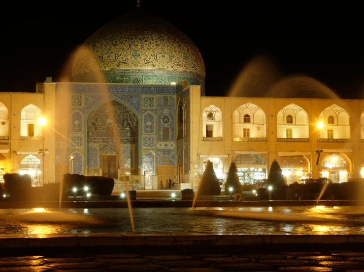 the fountain in front of a building with illuminated windows
