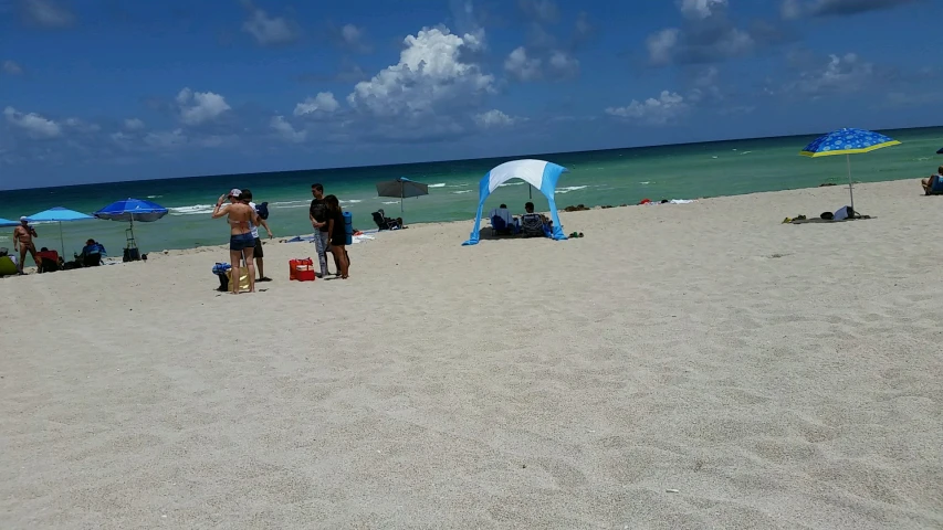 people on the beach standing around on towels