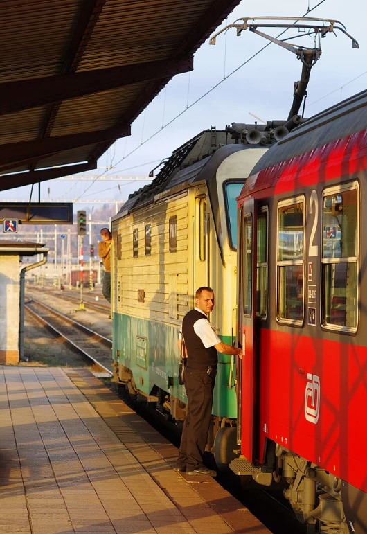 a man stands next to a train at the platform