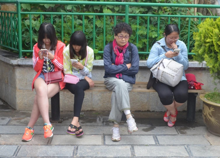 three asian ladies sit on a bench outside a building and text