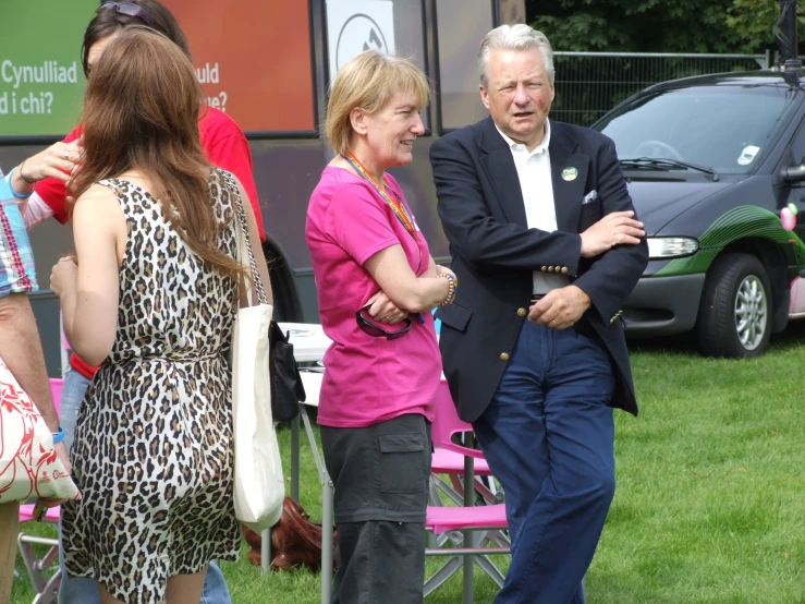 two women and a man walking around in some grass