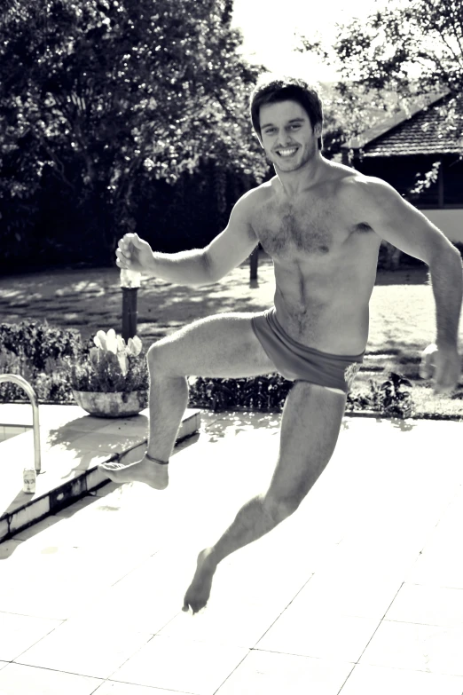 a guy jumping in the air near a swimming pool