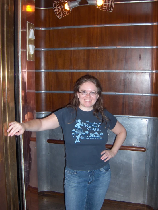 the young woman smiles as she leans out of a tall, shiny metal door