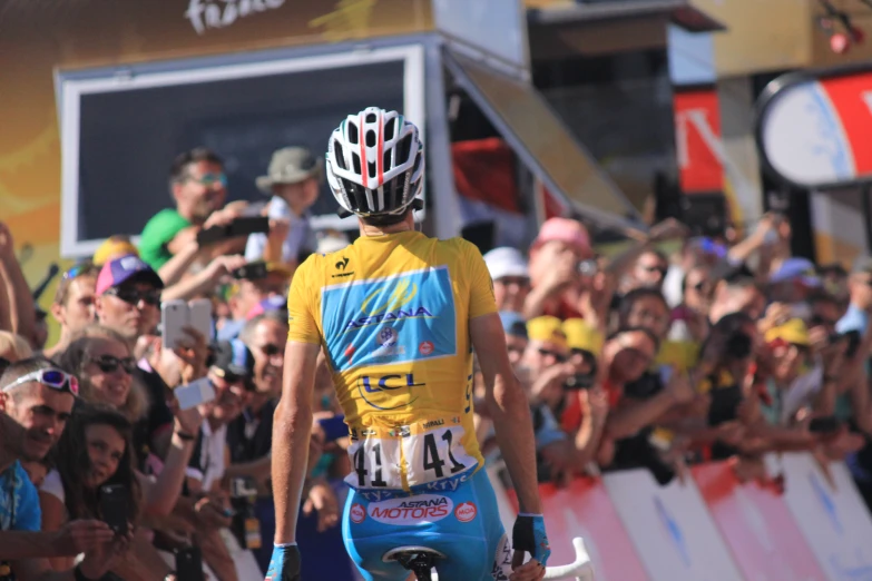 a man riding on the back of a bike past a crowd