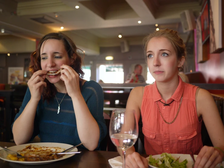 two women eat while sitting at a restaurant