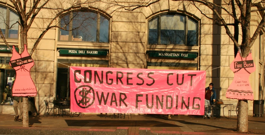a protest sign with pink letters on it