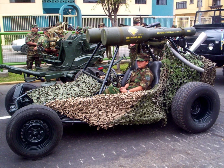 a car with a rifle on the front and soldiers in camouflage