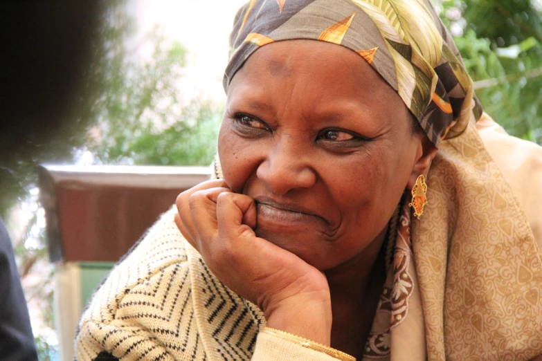 a woman with a headscarf has her hand on her face