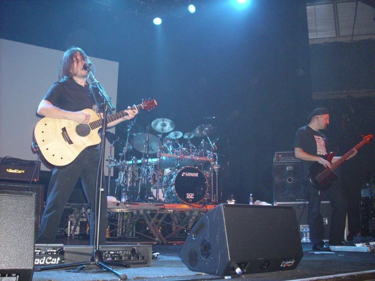 two men playing guitars on stage in the dark