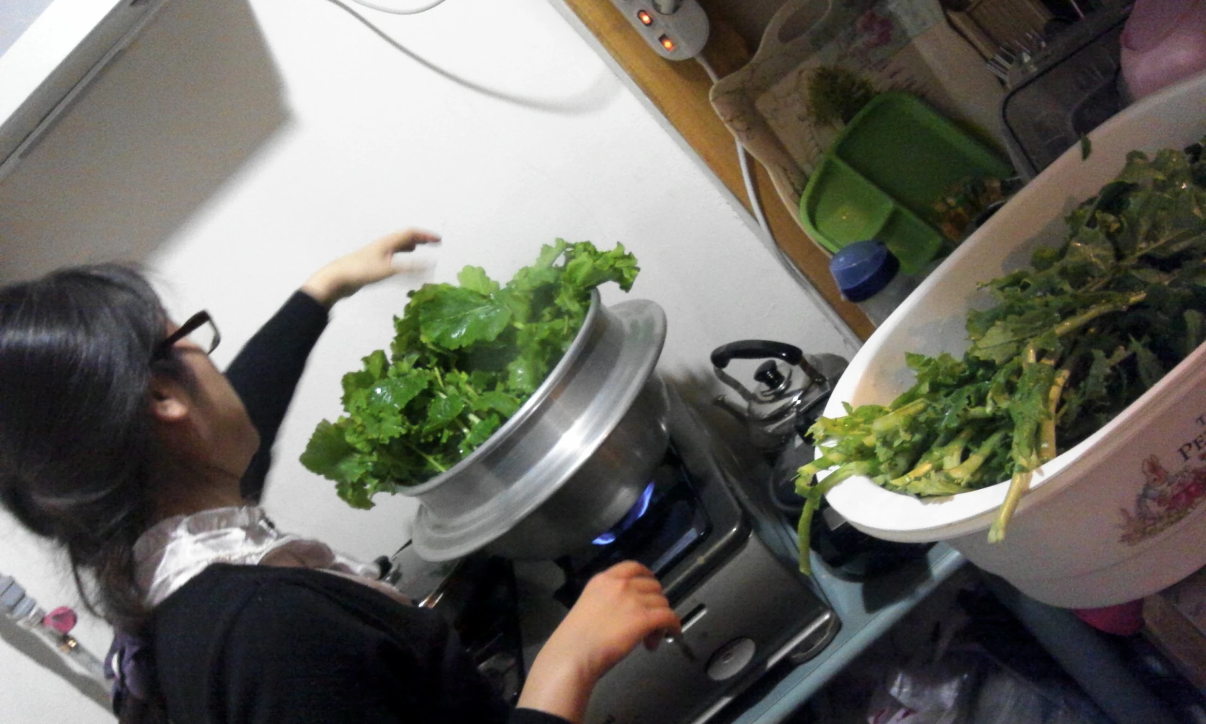 a woman is standing over a small stove top