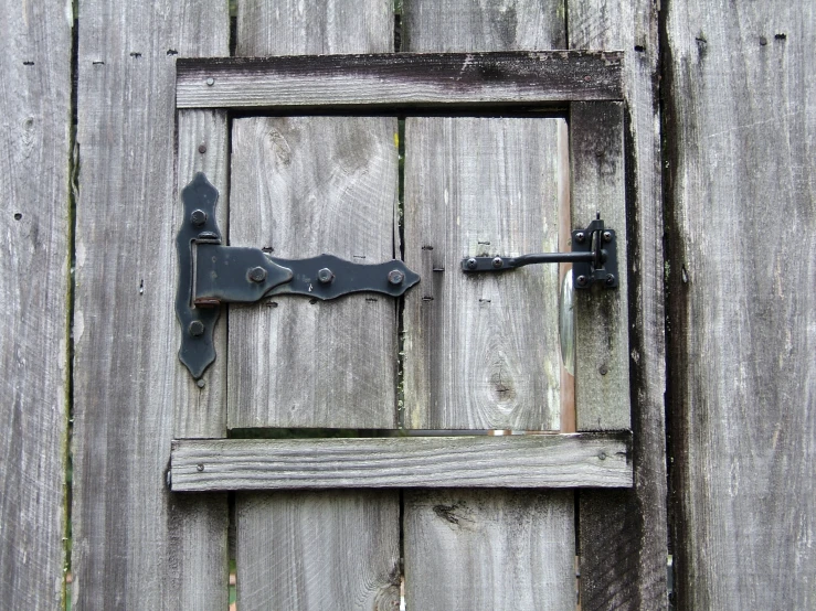 a wooden door with an old latch and pad lock