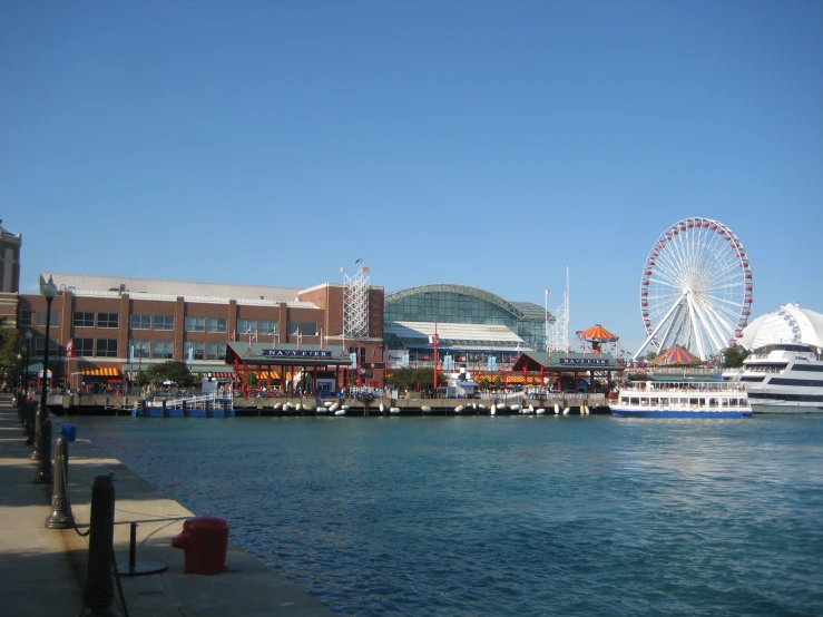 a large ferris wheel sits near the waters of the river