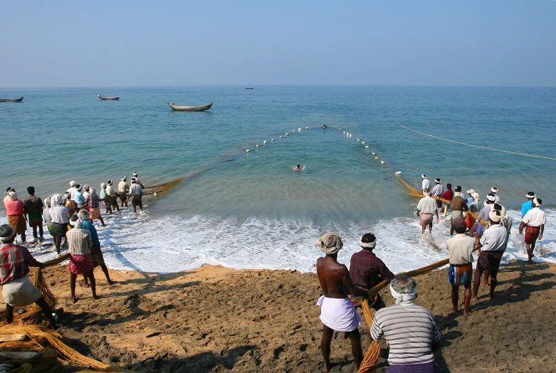 an ocean with many people at the edge, many are bathing