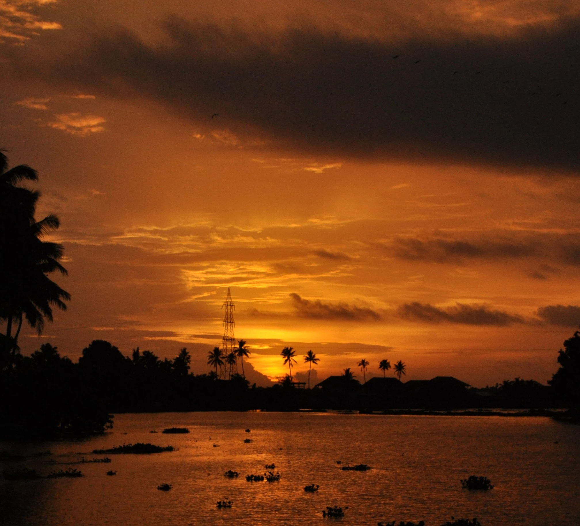 the setting sun in the ocean with some boats out at sea